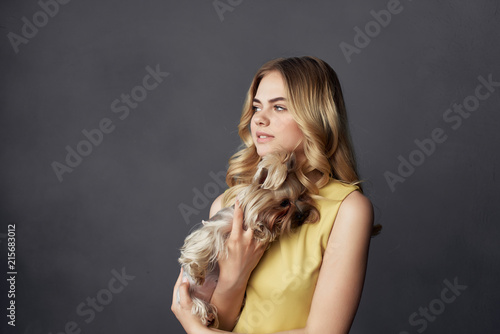 woman in a yellow dress holding a dog in her hand