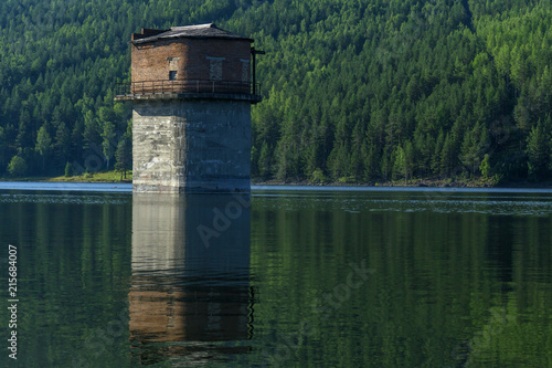 abandoned tower of the pumping station in the middle of a flooded quarry that has become a lake