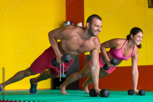 Beautiful fitness young sporty couple doing push ups together indoors.