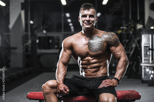 Handsome strong bodybuilder athletic men pumping up muscles with dumbbells