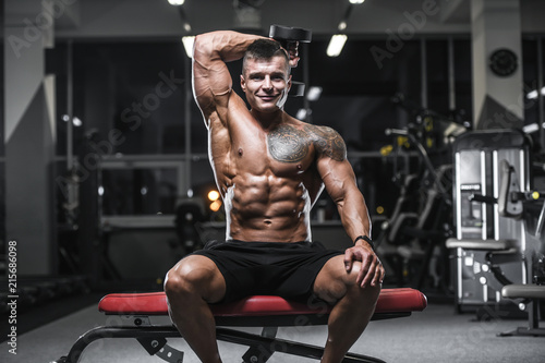 Handsome strong bodybuilder athletic men pumping up muscles with dumbbells © antondotsenko