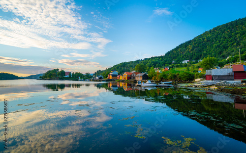 Houses in the harbor of Hosaner, on Osterøy island in Norway. Shot made at sundown with reflection of the colorful houses in the blue water