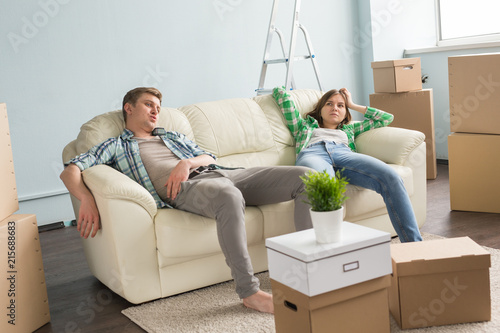 Home, people and family concept - Young cople having rest while moving in a new apartment