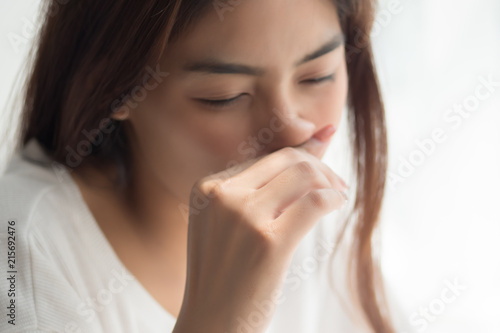 sick girl sniffle with runny nose; sick woman suffering from cold, flu, runny nose, trying to clear her nose; woman personal health care, pain, sickness concept; asian young adult woman model