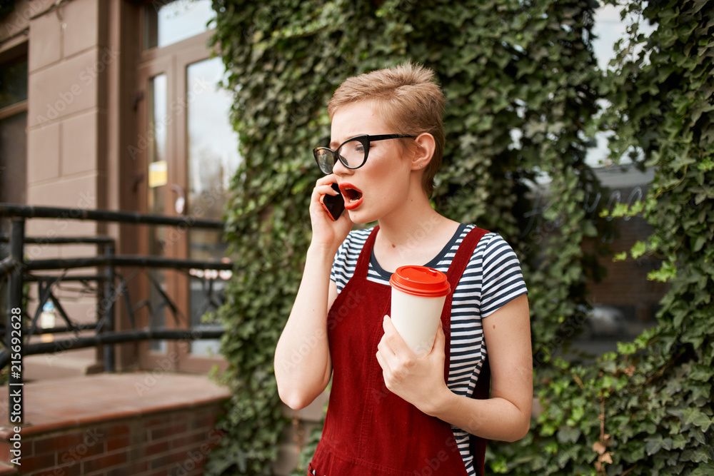 Fototapeta premium woman in glasses talking on the phone with coffee in the street
