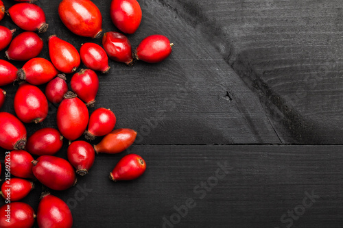 Rosehip on the black wooden table. Ingredient for medicinal tea, top view photo