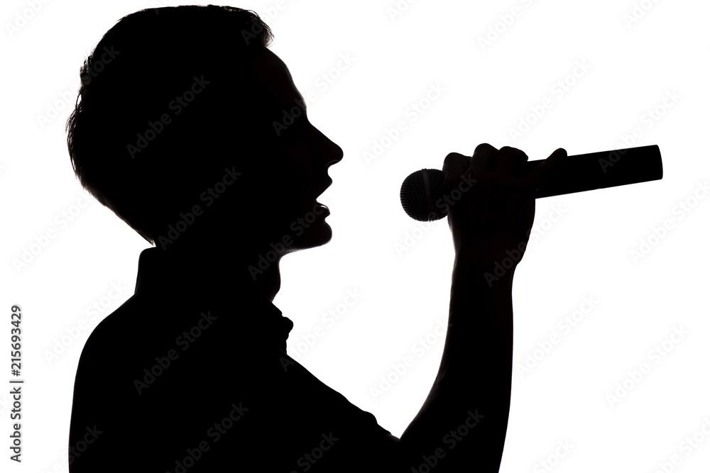 Silhouette of a young talented man singing into a microphon