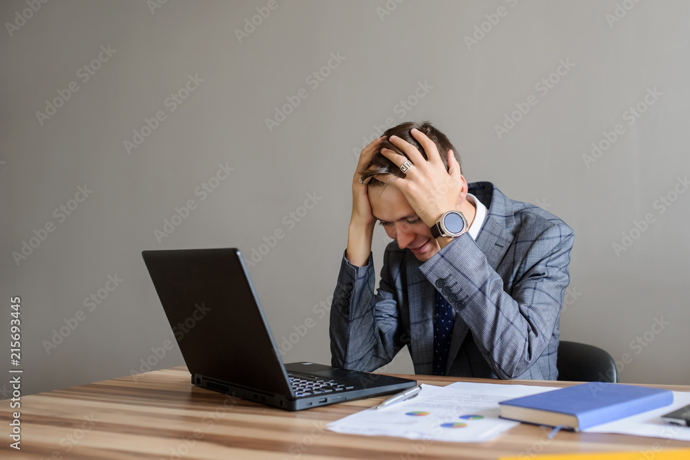 A business man at a office desk looking at the project on computer,hands on the head A business man at a office desk looking at the project on computer,hands on the head