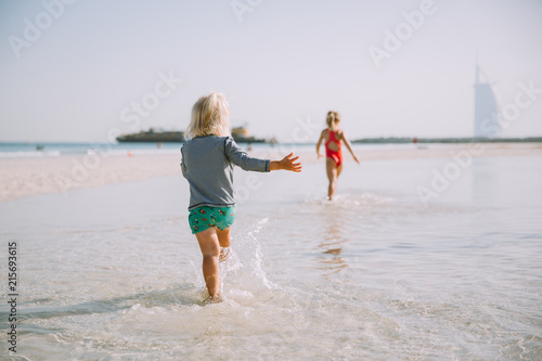 Two cute little sisters having fun and running  on sandy beach