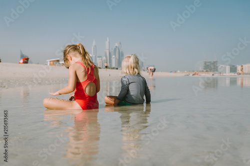 Photography Two cute little sisters bathing in sea on sandy beach