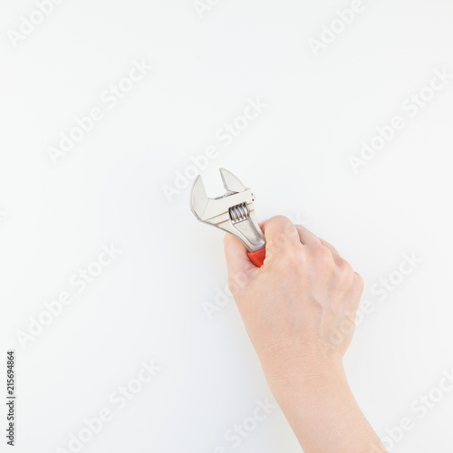 Female hand holding spanner on white background