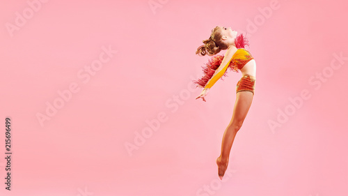 Taniec współczesny. Mała dziewczynka wykonuje skomplikowany taniec akrobatyczny. Taniec nowoczesny na jasnym kolorowym tle.