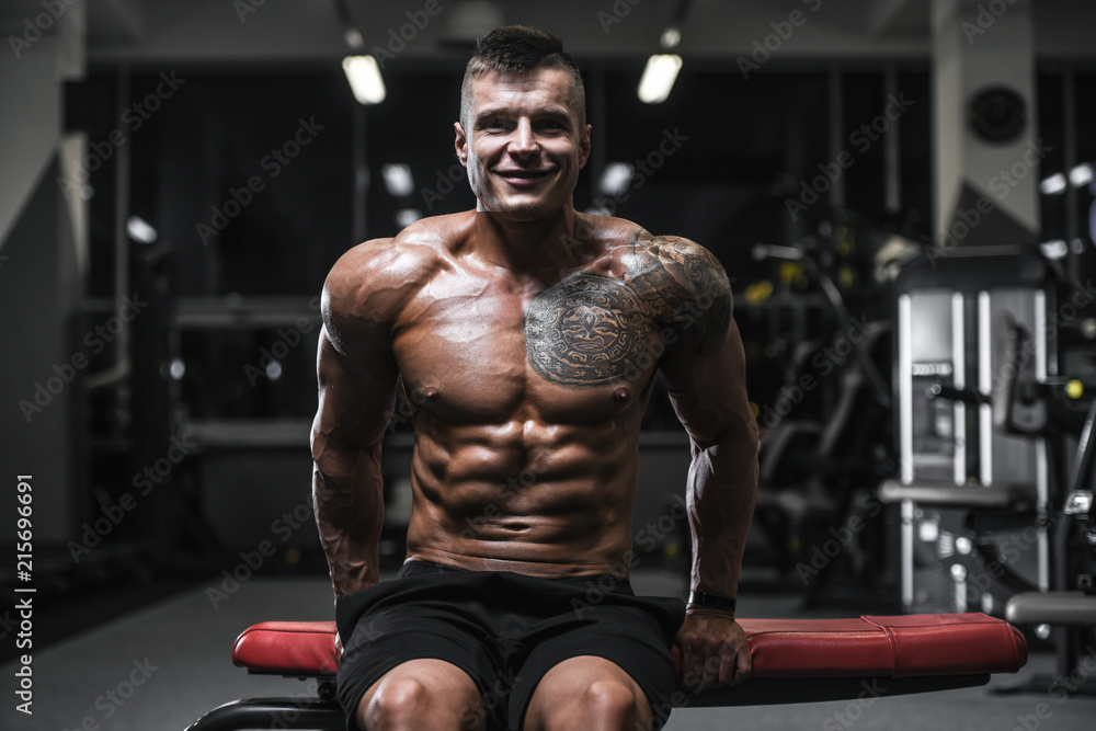 Fototapeta premium Handsome strong bodybuilder athletic men pumping up muscles with dumbbells
