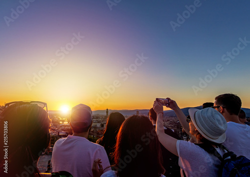 Happy people tourists taking pictures of sunset summer city landscape, rear view