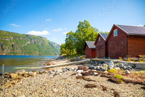 Typical norwegian wooden rorbu hut on the fjord beach in sunny summer day, Norway photo