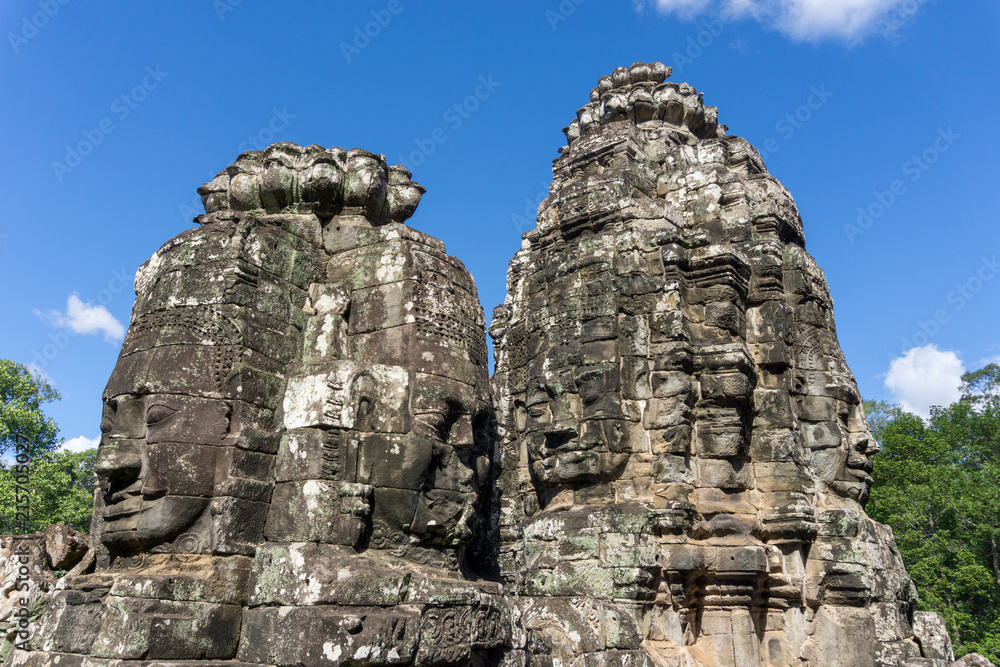 Stone faces of the ancient Bayon Temple against blue sky, Angkor Wat, Cambodia