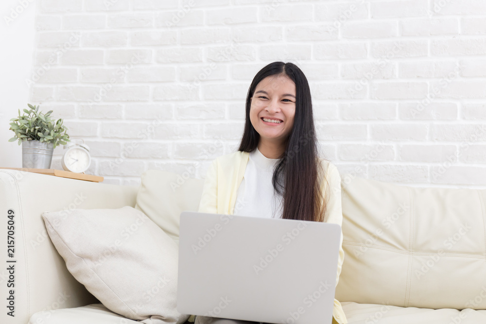 Asian woman using notebook on sofa in white room Asian woman using notebook on sofa in white room