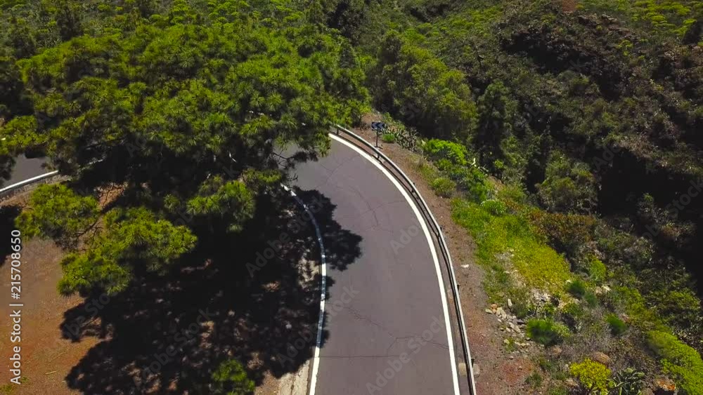 Top view of a car and cyclist rides along a mountain road on Tenerife, Canary Islands, Spain. Way to the Teide volcano, Teide National Park Top view of a car and cyclist rides along a mountain road on Tenerife, Canary Islands, Spain. Way to the Teide volcano, Teide National Park