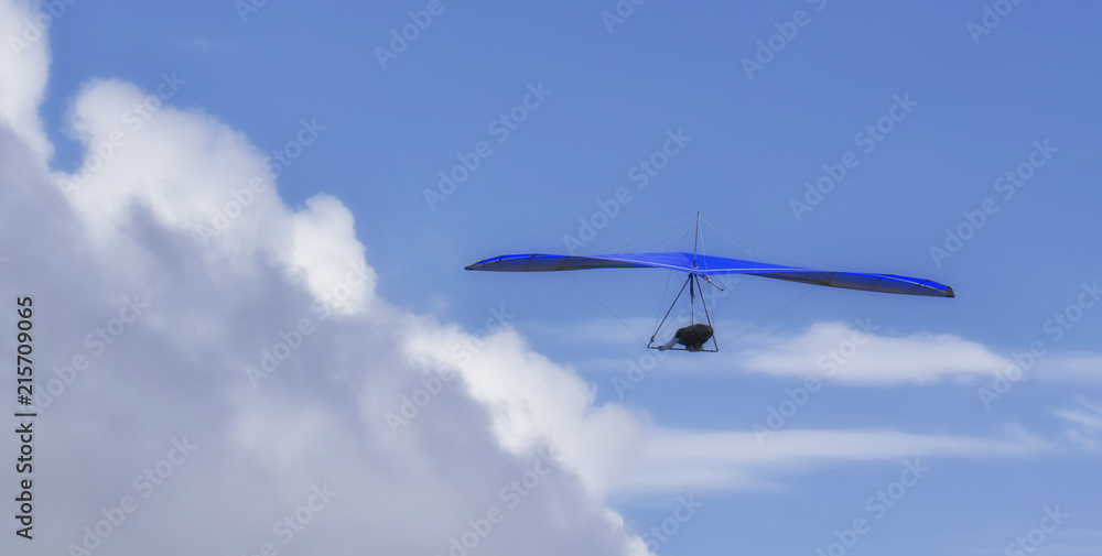 Hang Glider flying in the sky on a sunny bright blue day Hang Glider flying in the sky on a sunny bright blue day