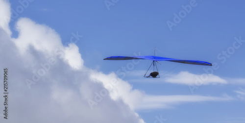 Hang Glider flying in the sky on a sunny bright blue day