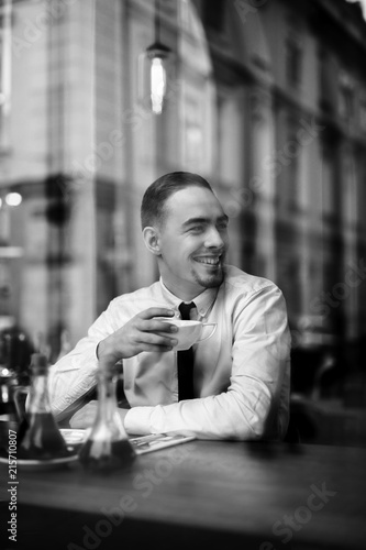 Smiling businessman drink coffe under window reflections photo