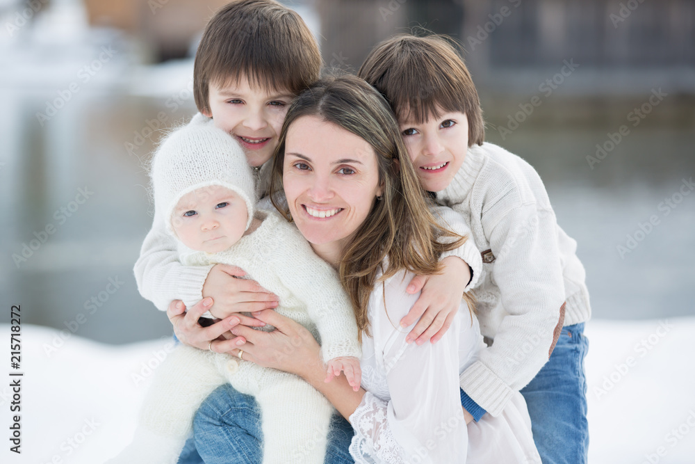 Beautiful mother in white dress and her cute children, three boys Beautiful mother in white dress and her cute children, three boys