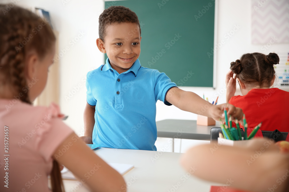 Cute little child taking his classmate's pencil at school Cute little child taking his classmate's pencil at school
