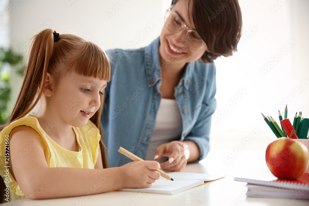 Female teacher helping child with assignment at school Female teacher helping child with assignment at school