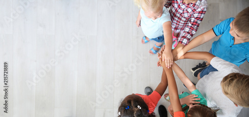 Little children putting their hands together indoors, top view. Unity concept photo
