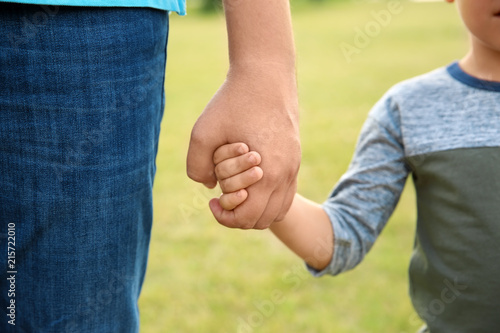 Man holding hands with his child outdoors, closeup. Happy family