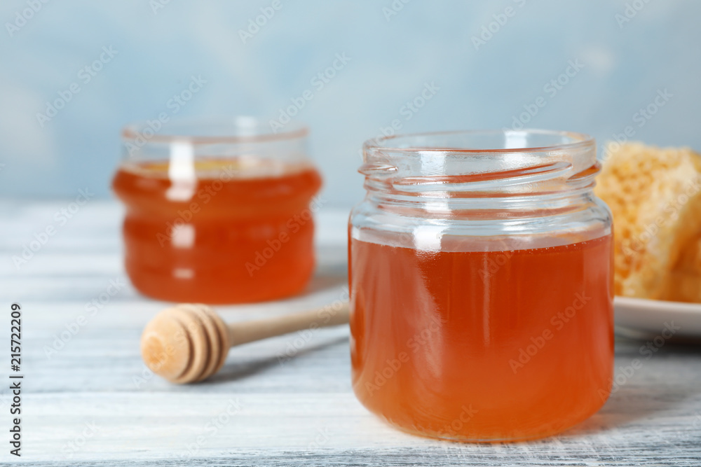 Glass jar with sweet honey and dipper on table, closeup Glass jar with sweet honey and dipper on table, closeup