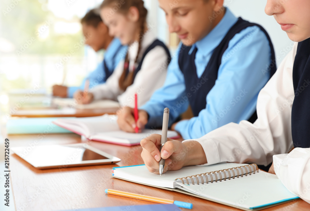 Teenage students in stylish school uniform at desk, closeup Teenage students in stylish school uniform at desk, closeup
