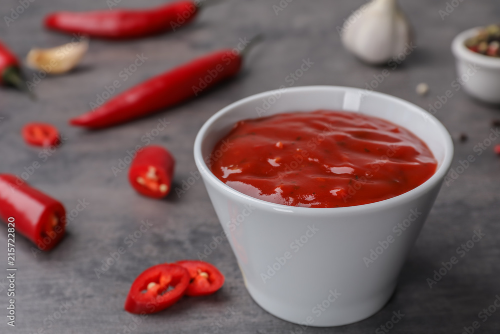 Bowl with hot chili sauce on gray table Bowl with hot chili sauce on gray table