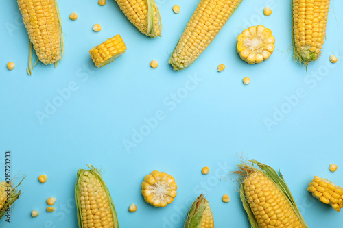 Flat lay composition with tasty sweet corn cobs on color background