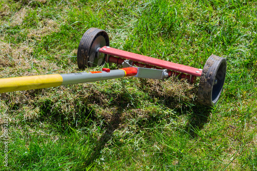 Cleaning up the grass with a rake. Aerating and scarifying the lawn in the garden. Remove old grass. Manual scarification of lawn with fan rakes and wheels. 