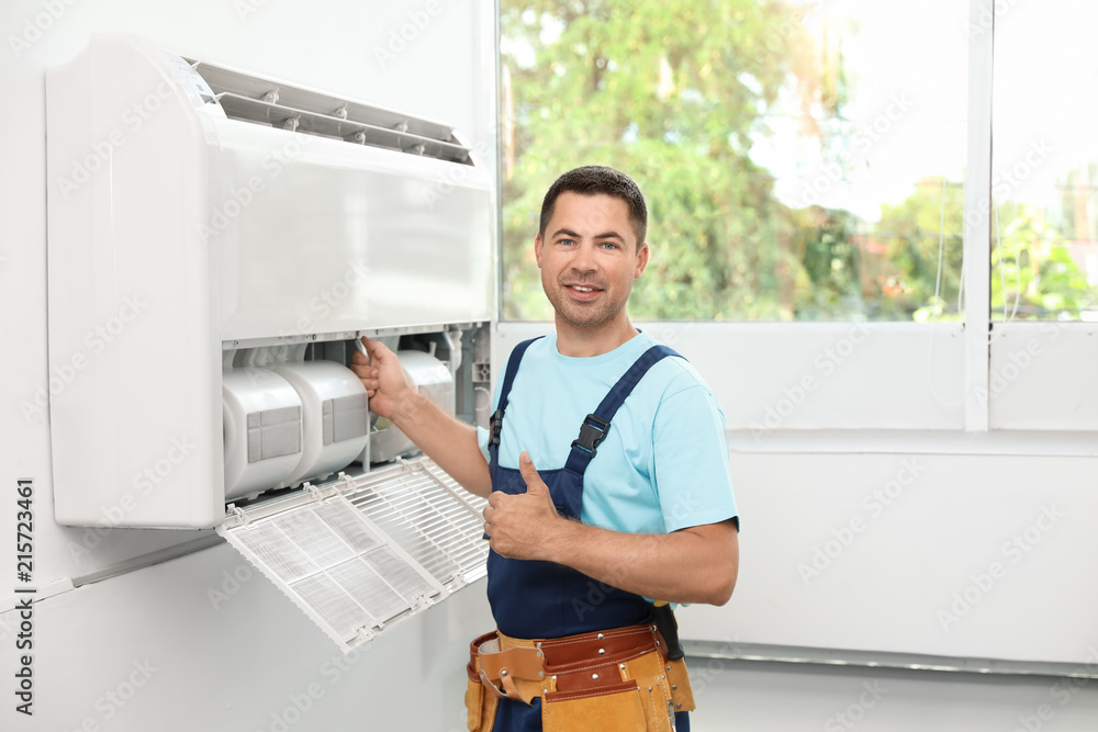 Male technician standing near air conditioner indoors