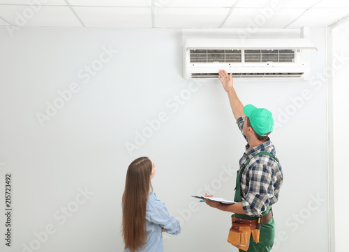 Male technician speaking with woman about air conditioner indoors