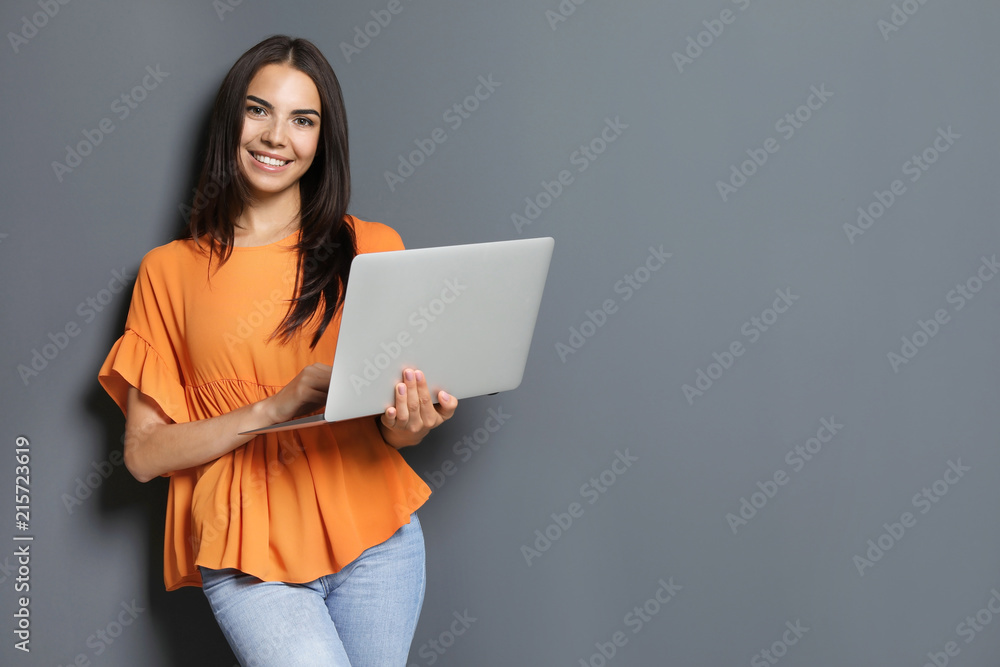 Young woman with modern laptop on grey background Young woman with modern laptop on grey background