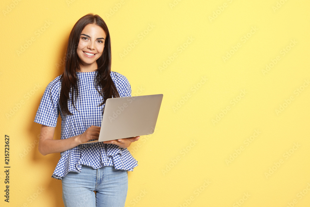 Naklejka premium Young woman with modern laptop on color background