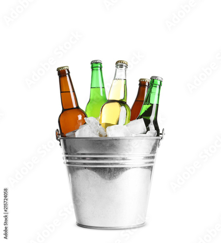 Bottles with different types of beer and ice in metal bucket on white background