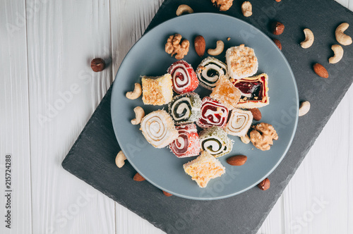 Foto Traditional oriental sweets and nuts: hazelnuts, cashews on a white wooden background