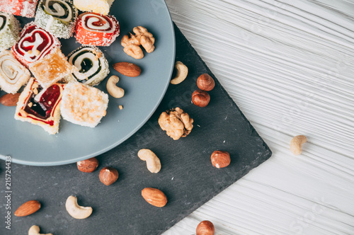 Foto Traditional oriental sweets and nuts: hazelnuts, cashews on a white wooden background