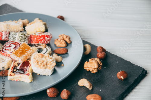Bilde på lerret Traditional oriental sweets and nuts: hazelnuts, cashews on a white wooden background