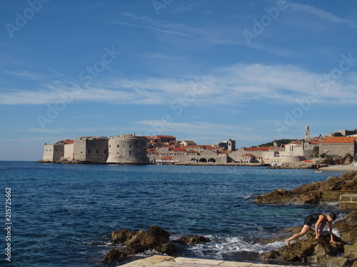 A beautiful landscape seascape over the rocky coastline and sea to the ancient port of Dubrovnik in Croatia to the castle fortress where Game of Thrones is filmed in Summer with bright blue sky