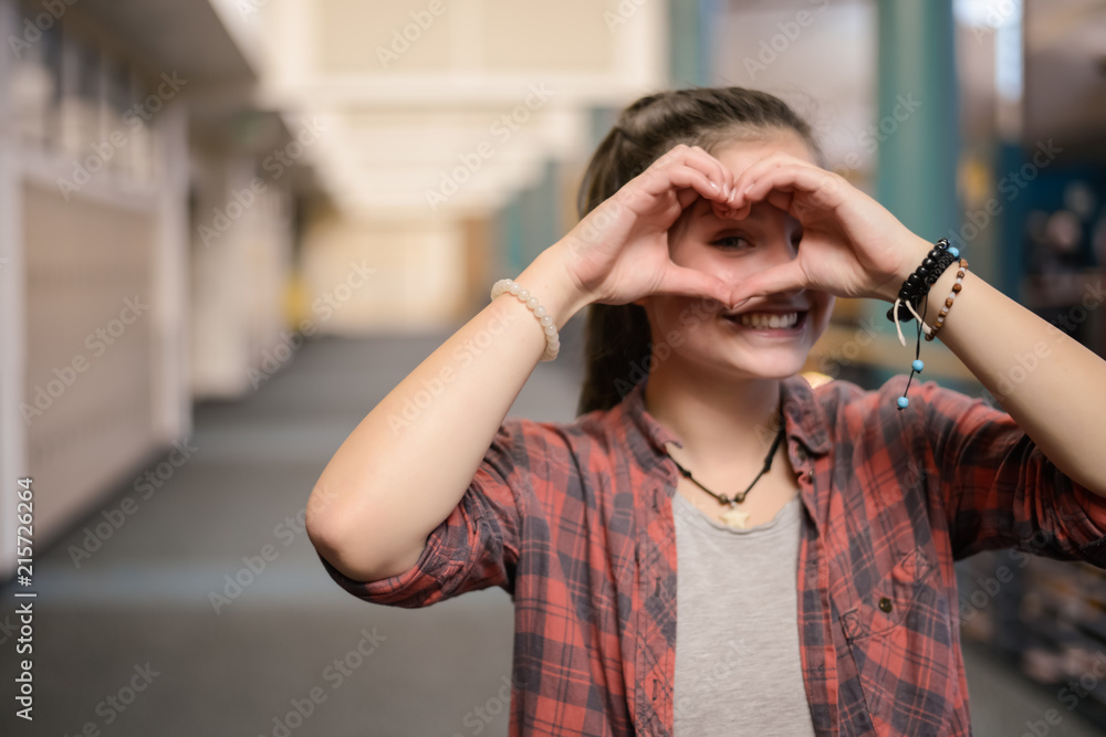 Teen girl showing heart hands at high school