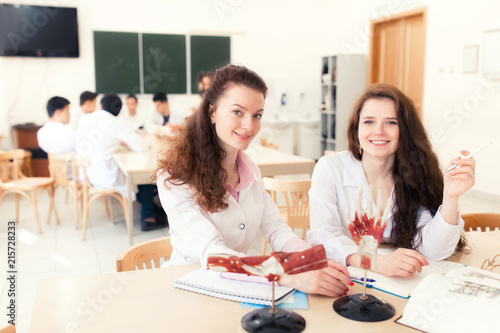 group student of medicine examining anatomical model in labin the form of a written examination  sitting in a modern classroom. The structure of the hand. emotional porneter girls doctors.