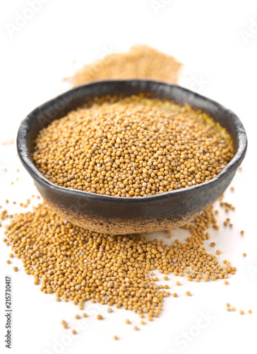 Heap of raw, unprocessed mustard seed kernels in bowl on white