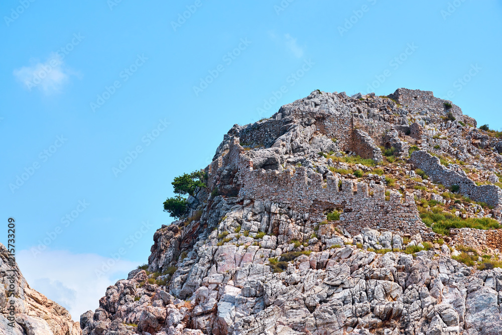 Rocks against a blue sky and wall of medieval castle in Alanya, Turkey.