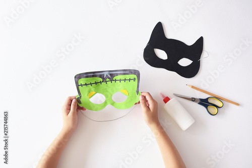 Making masks  paper  holiday Halloween Monster's  mask Black cat  Hands top view 