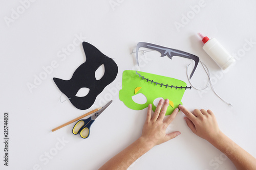 Making masks  paper  holiday Halloween Monster's  mask Black cat  Hands top view 